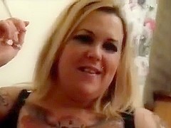 Tattooed blonde smokes cigarette and sucks penis