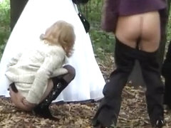 Three ladies help bride pee outdoors