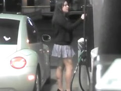 Short skirt girl putting gas in car