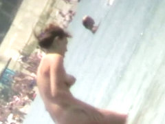 Nudist video at the beach has shy girl playing in the water