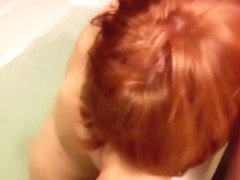 Bigbreasted redhead gives blowjob while sitting in a bath
